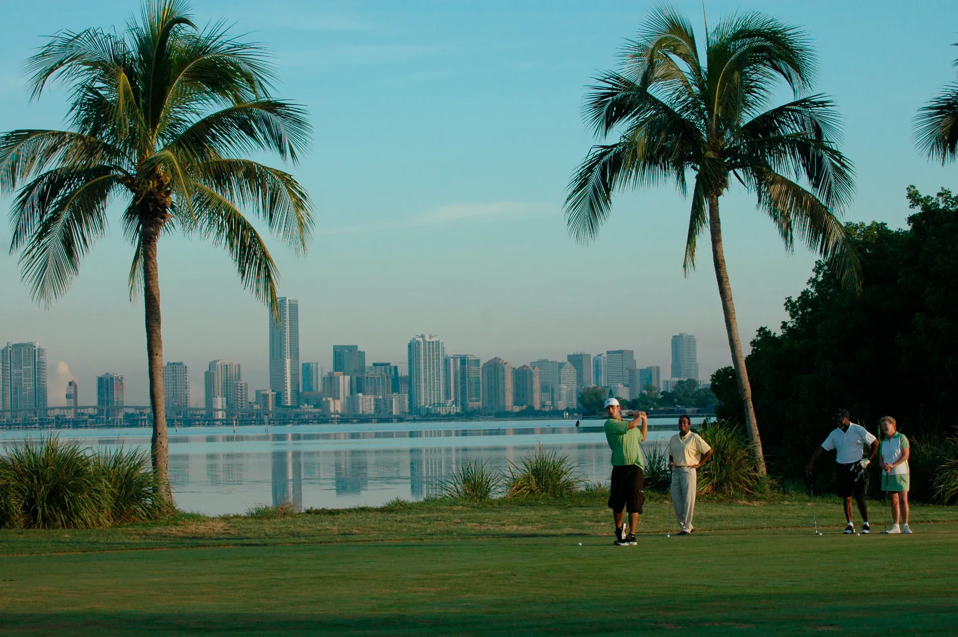 Golfers on a Miami course with the downtown skyline across the water
